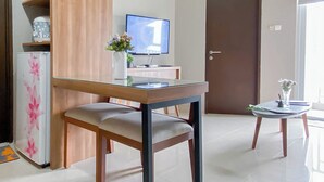 Ein modernes Wohnzimmer mit einem Esstisch mit Glasplatte, einem Fernseher und einem kleinen Beistelltisch mit einer Vase.