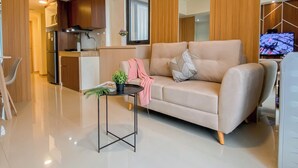 Un salon moderne avec un canapé, une petite table ornée d’une plante et un téléviseur.