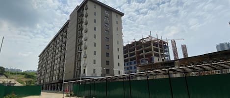 A multi-story building with balconies and a construction site nearby.