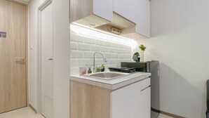 A modern kitchen with white cabinets, a stainless steel sink, and a built-in oven. - Best Deal And Homey Studio At Meikarta Apartment (Cikarang)