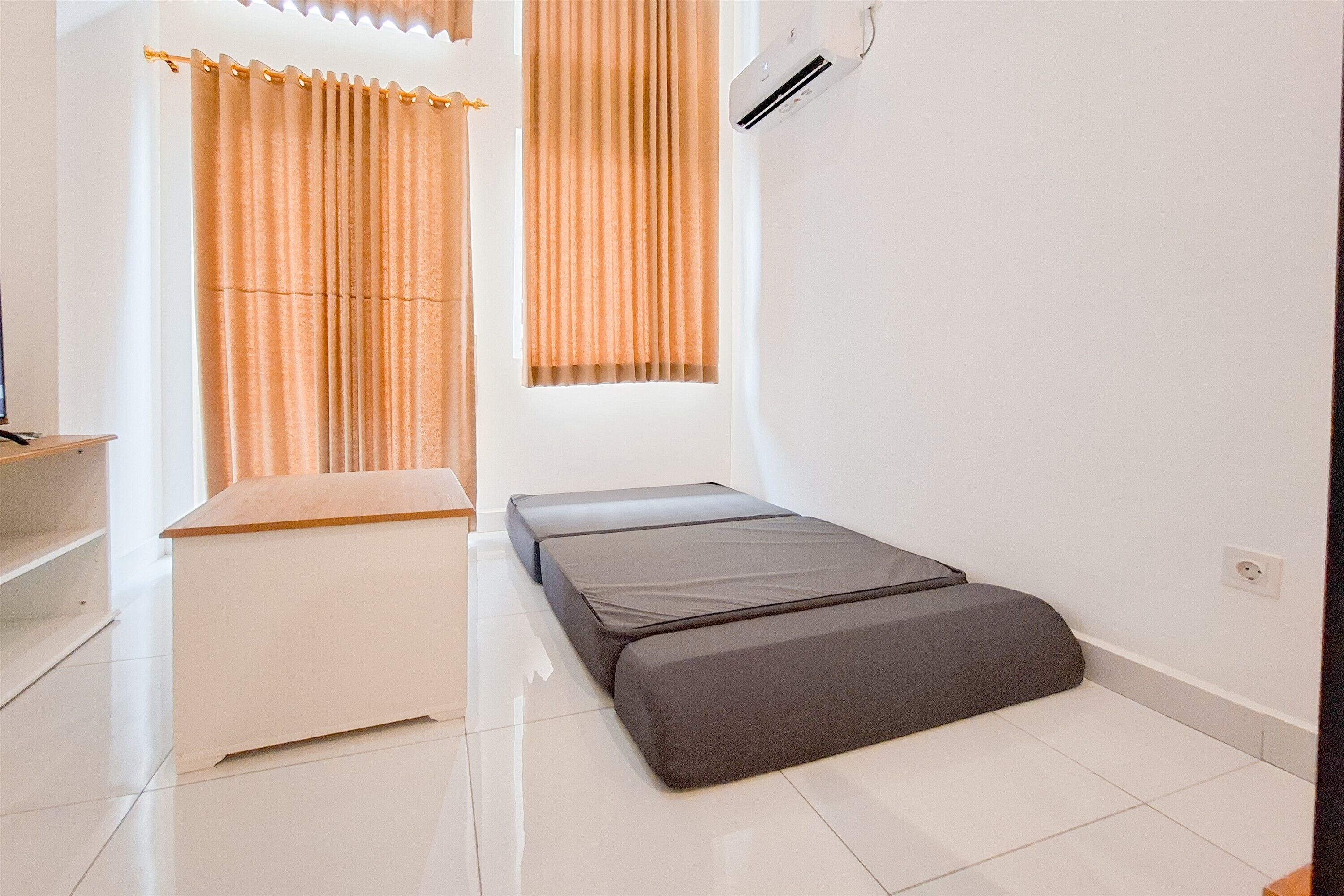 A small, clean room with a bed, a white chest of drawers, and a window with curtains.