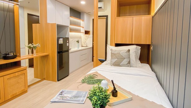 A compact bedroom with a bed, bedside table, and a small kitchenette. - Chic And Cozy Studio At Apartment Transpark Cibubur (Depok)