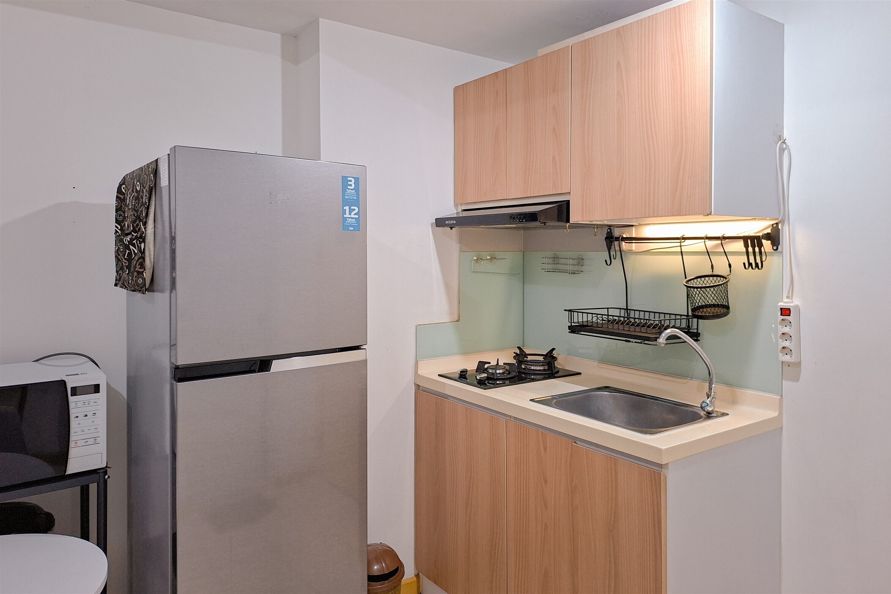 A compact kitchen with a refrigerator, stove, sink, and microwave.