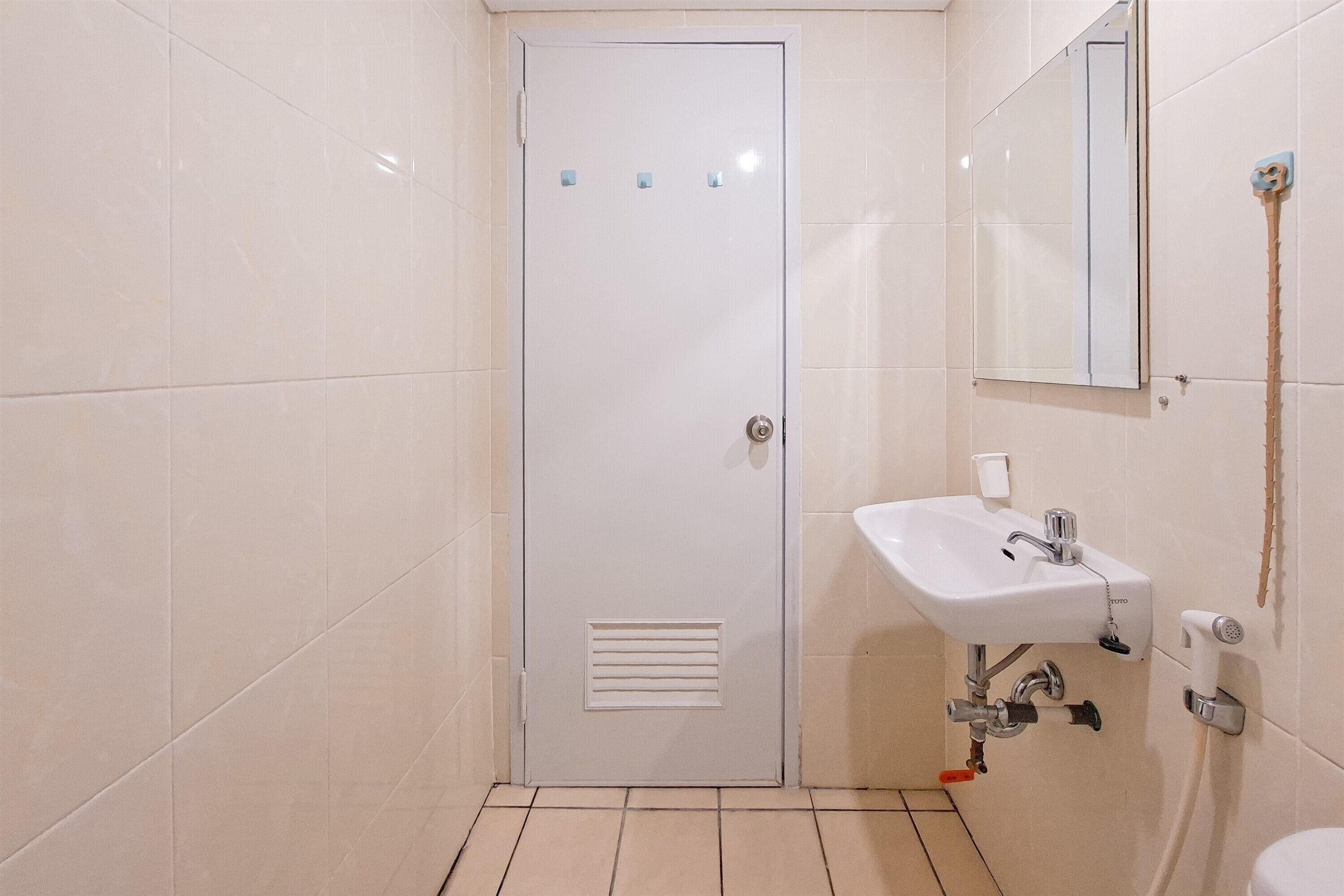 A bathroom with a white door, a sink, and a mirror.