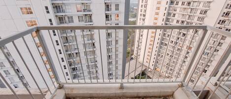 A high-rise residential building with multiple balconies, a tiled floor, and a metal railing.