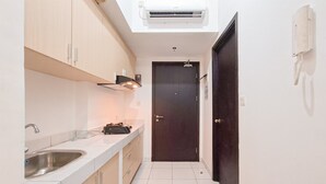 Una cocina estrecha con horno empotrado, un lavamanos y una puerta oscura.