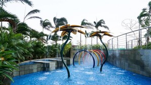 A water park with a pool, water slides, and palm trees. - Cozy Stay Studio At West Vista Apartment (Jakarta)