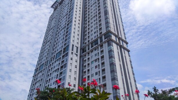 A tall, modern high-rise building with a grid of windows and balconies. - Cozy Stay Studio At West Vista Apartment (Jakarta)