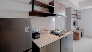 A modern kitchen with a built-in refrigerator, a gas stove, and a sink. There are wooden cabinets and a countertop with a marble backsplash. - Cozy Stay Studio At West Vista Apartment (Jakarta)