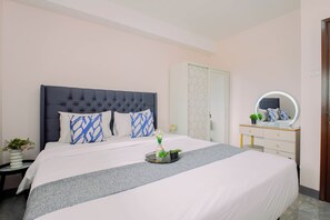 Une chambre à coucher avec un grand lit, une table de chevet ornée d’un vase de fleurs, une commode avec un miroir et une porte à motifs géométriques.