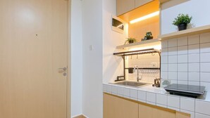 Une cuisine moderne avec un évier encastré, un plan de travail agrémenté d’une petite plante et une porte en bois.