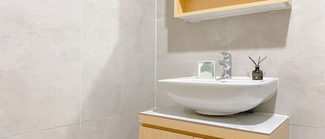 A bathroom with a white sink, wooden cabinet, and a mirror above the sink.