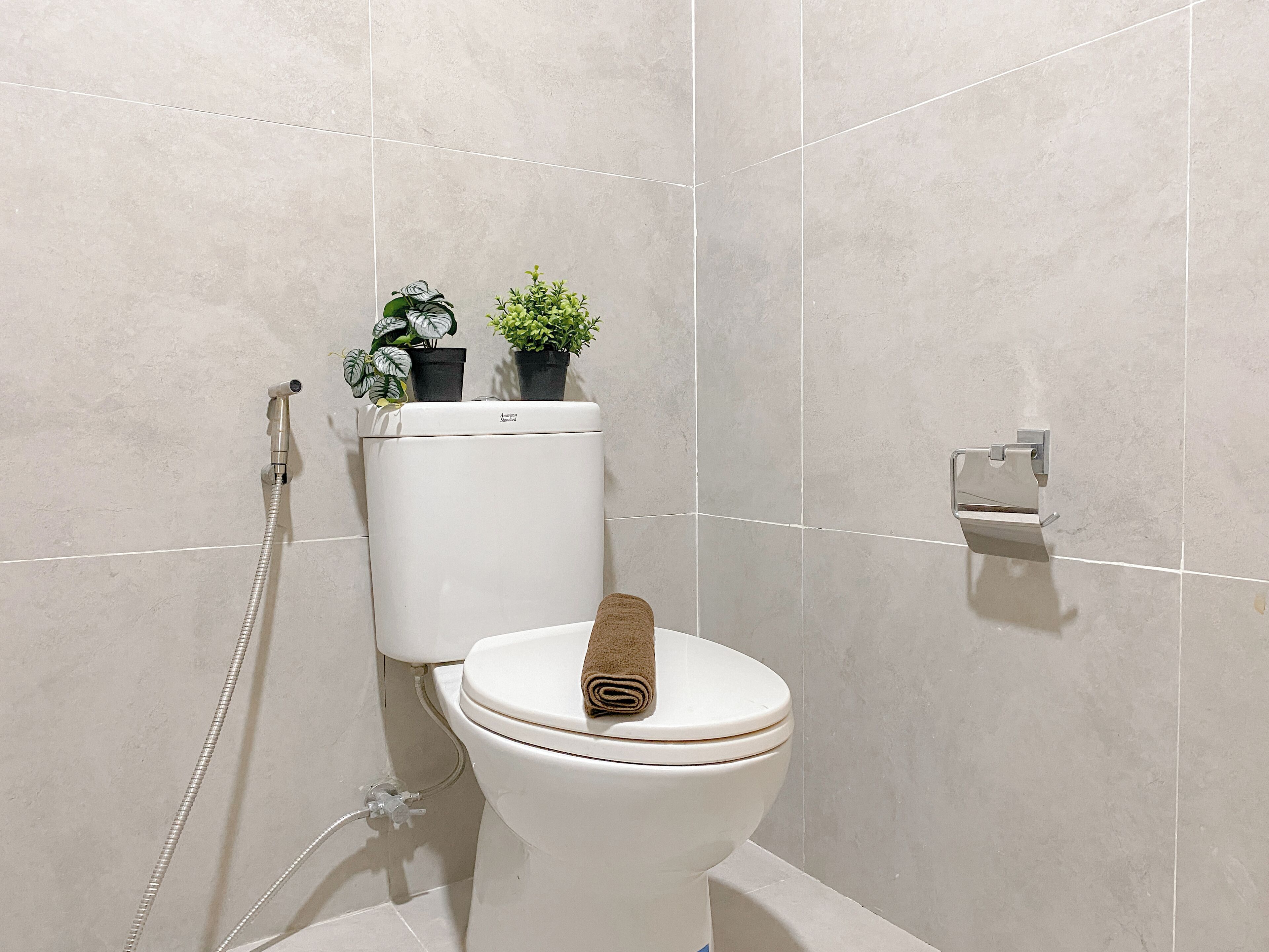 A modern bathroom with a toilet, a shower, and a toilet paper holder.