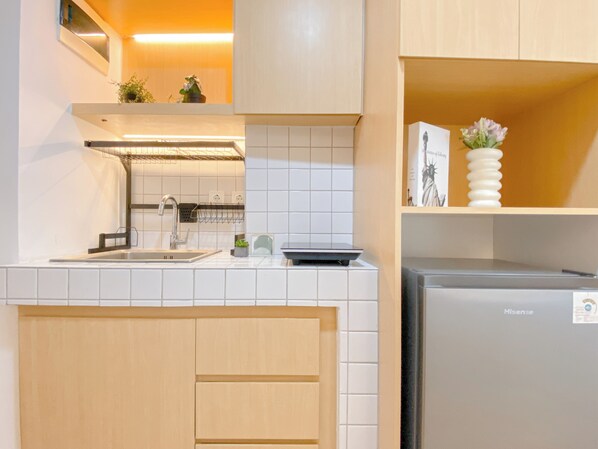 A modern kitchen with white tiles, a stainless steel sink, a built-in oven, and wooden cabinets.