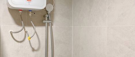 A bathroom with a white water heater, a showerhead, and a handheld shower attachment.