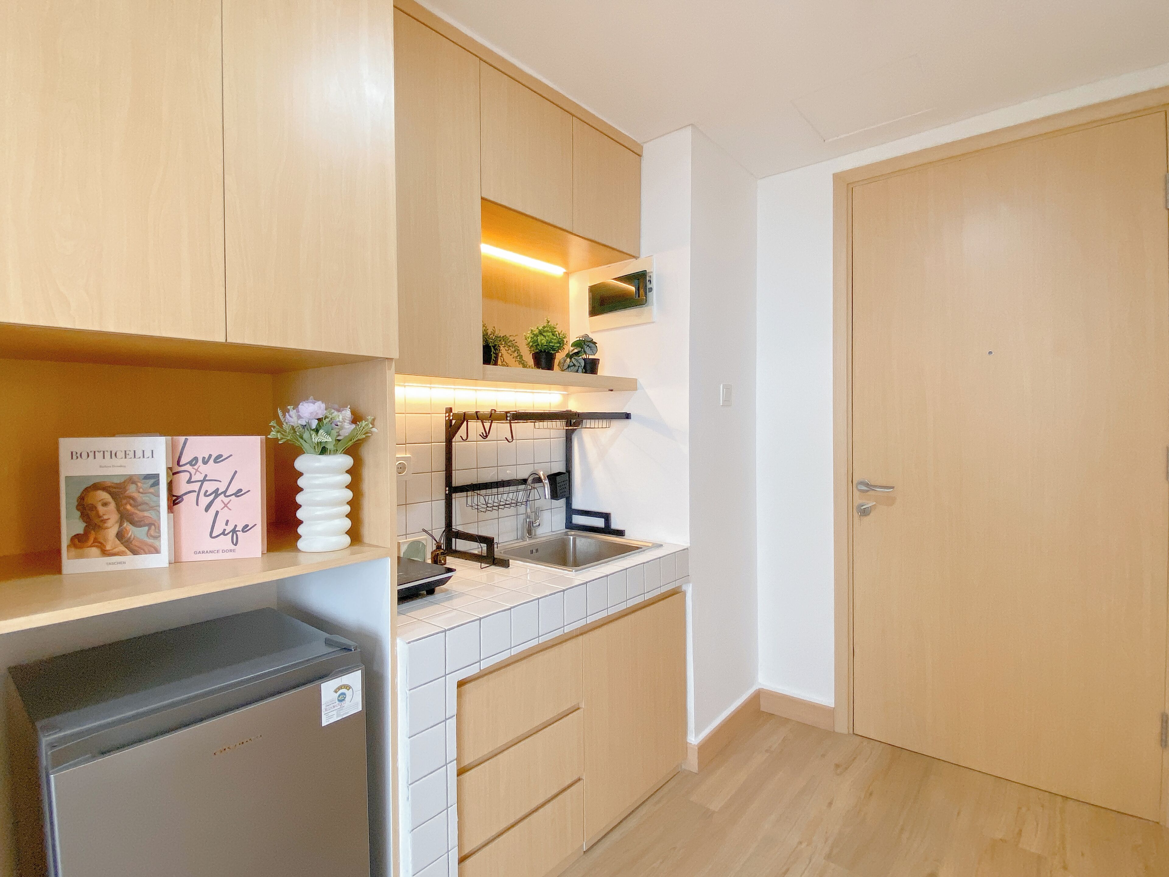 A modern kitchen with wooden cabinets, a built-in oven, a sink, and a refrigerator.