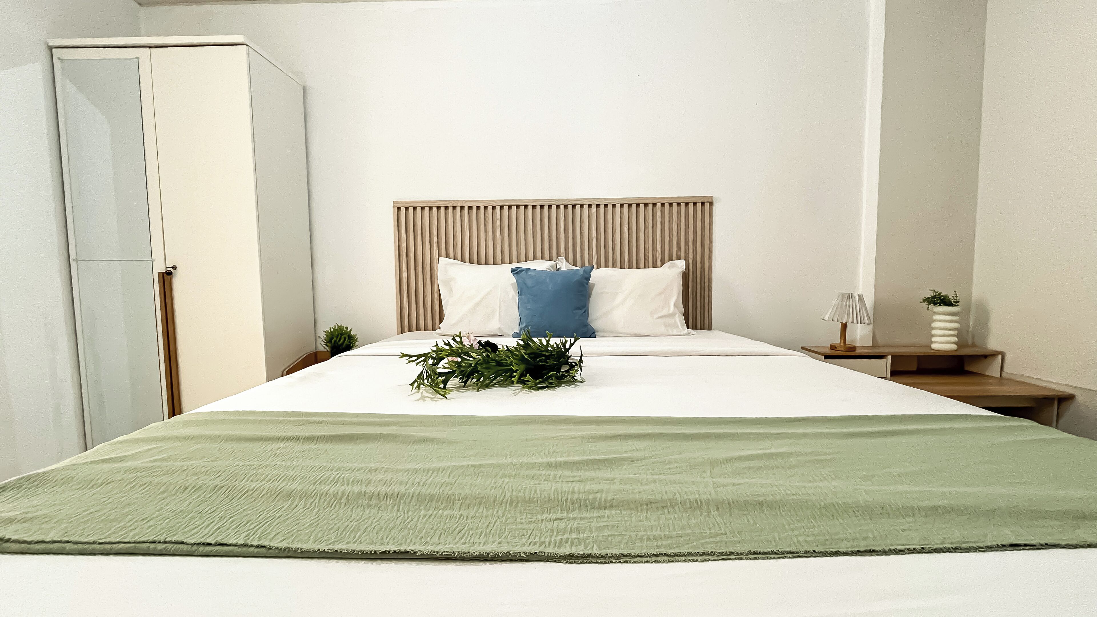 Quarto bem arrumado com cama, mesa de cabeceira e guarda-roupa.