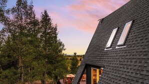Ein modernes Haus mit einem steilen Dach, einer Holzdiele und einem großen Fenster.