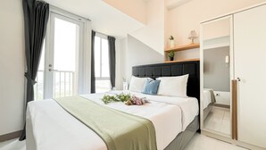 Un dormitorio moderno con una cama grande, una mesita de noche, una planta pequeña y un espejo.