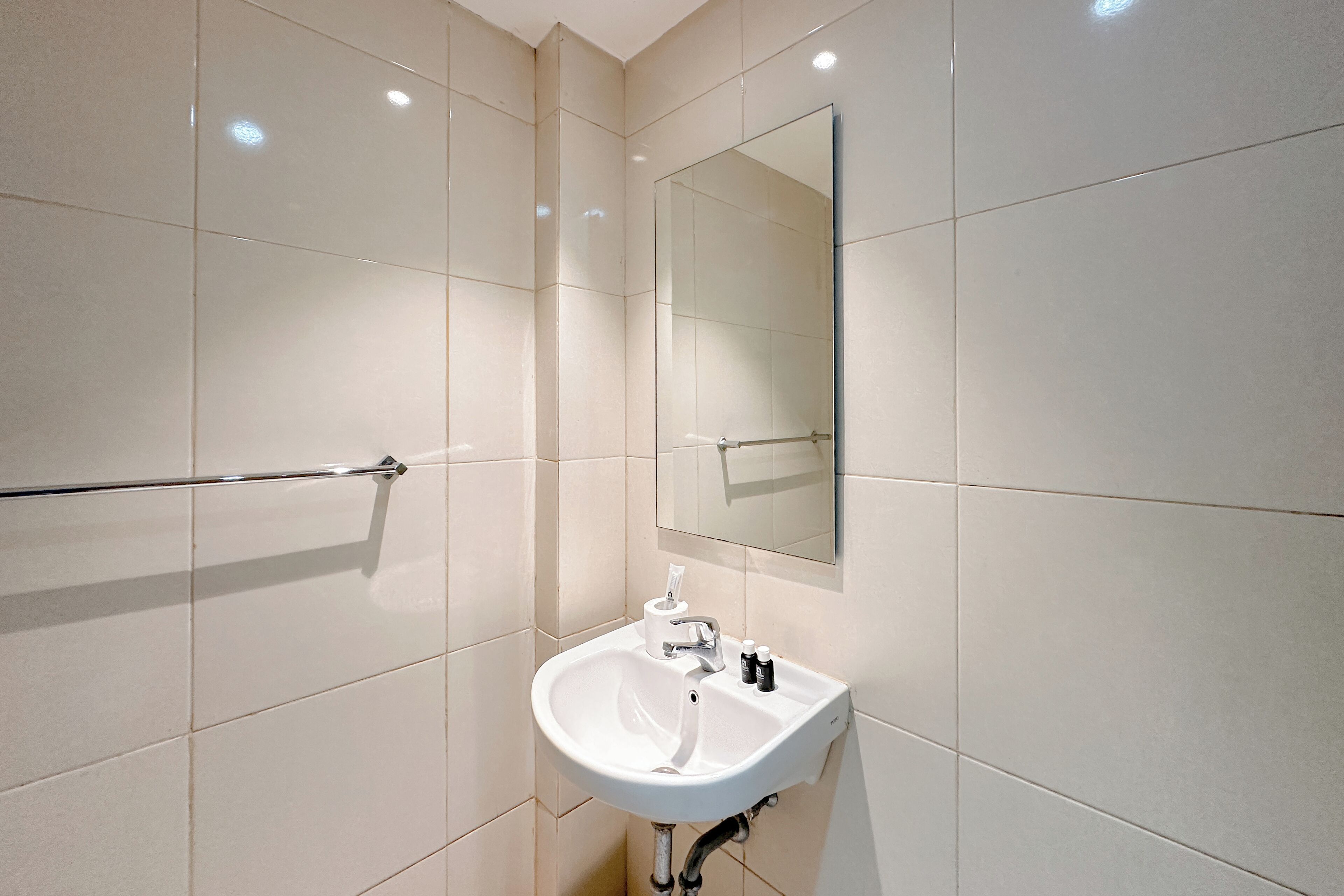A bathroom with a white sink, a mirror, and a towel rack.