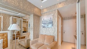 Un soggiorno moderno con un divano beige, una parete divisoria in vetro e un quadro con una veduta urbana.