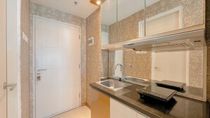 Una cucina compatta con lavello in acciaio inossidabile, forno a incasso e microonde.