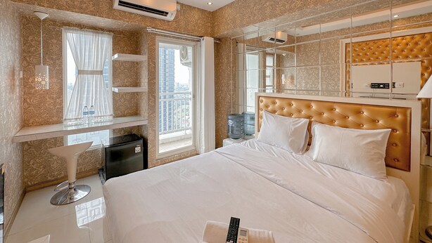 Camera d'albergo con un letto grande, un comò con specchio, una finestra con tende e un minibar.
