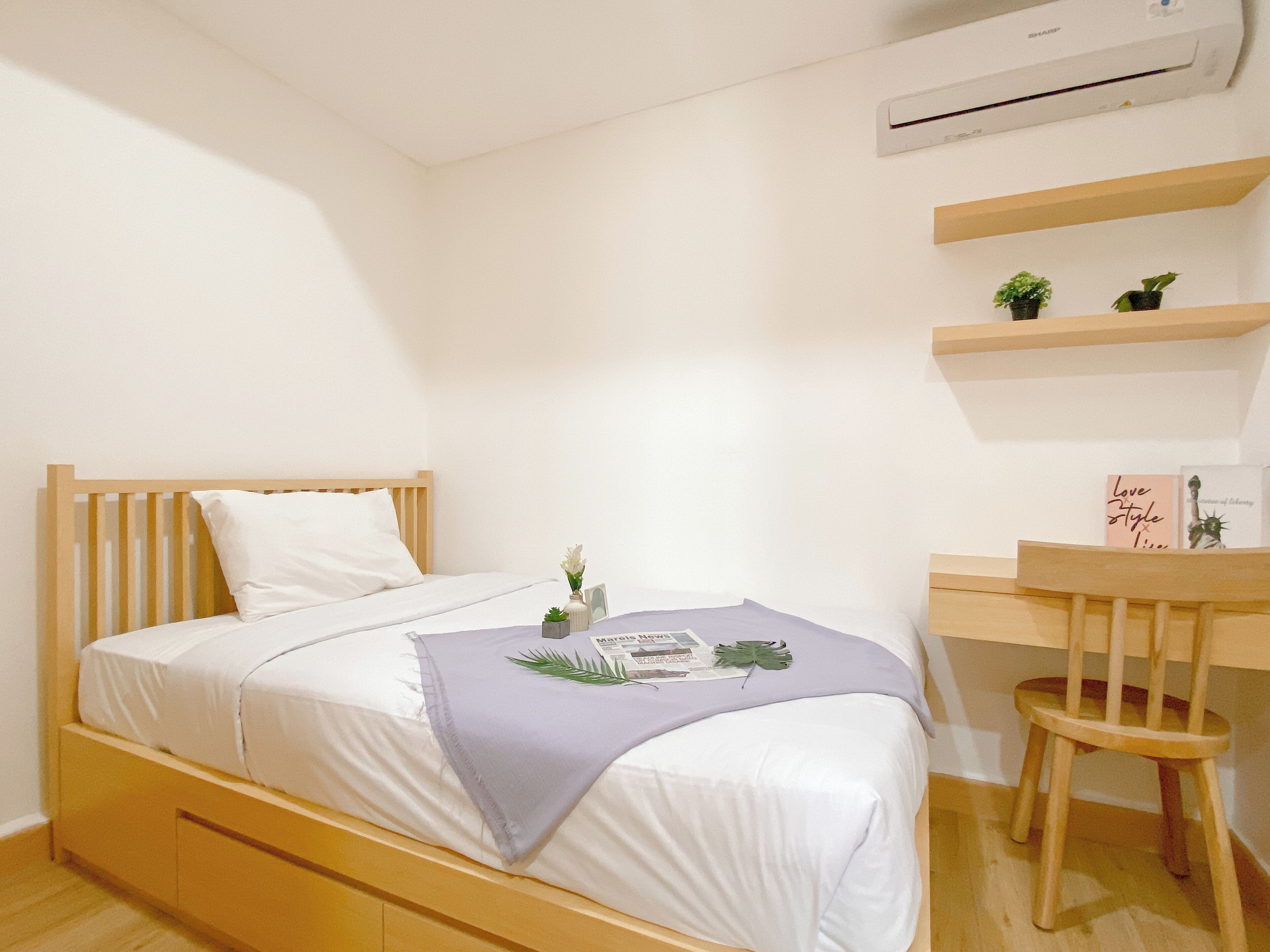 Un dormitorio ordenado con cama, escritorio y silla.