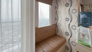A room with a cushioned bench, a water dispenser, and a window with a view of a cityscape.