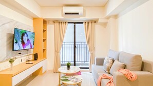 A modern living room with a flat-screen TV, a sofa, a small round table, and a balcony with curtains. - Spacious 2Br At Meikarta Apartment (Cikarang)