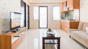 Una sala de estar con televisor, una mesa de centro, un sofá y armarios de madera.