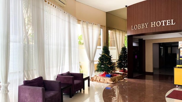 Un vestíbulo con un árbol de Navidad, sofás morados y un letrero que dice 'Lobby Hotel'.