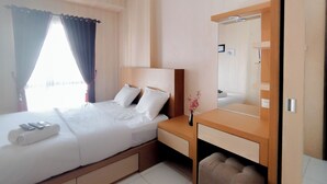 A hotel room with a bed, bedside table, and a mirror. - 1Br Apartment At Tamansari Prospero Sidoarjo Near Lippo Mall Sidoarjo (Sidoarjo)