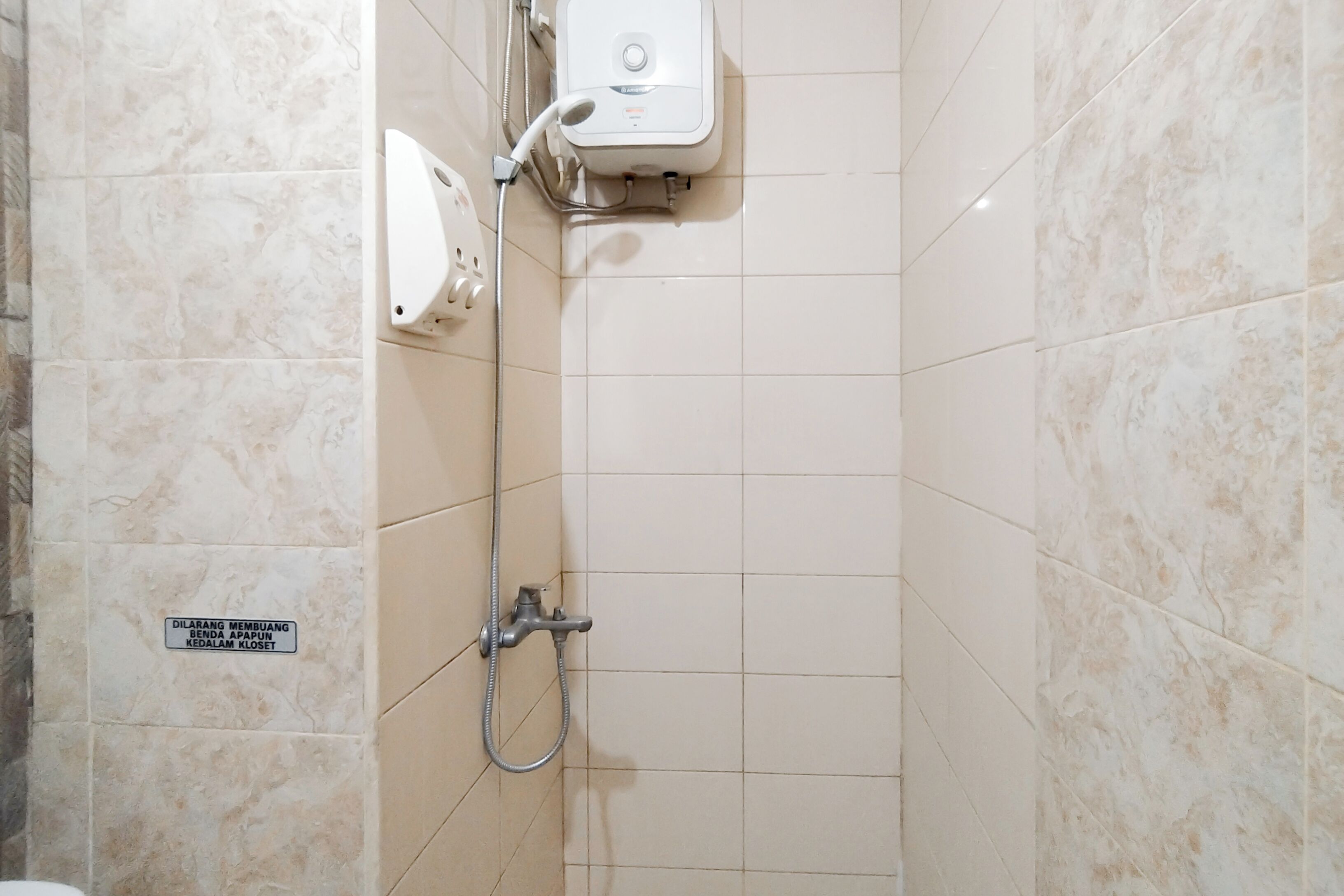 A bathroom with a shower, a toilet, and a sign on the wall.