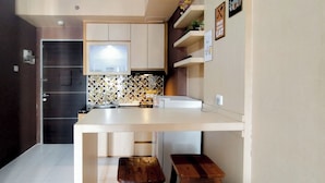 A modern kitchen with white cabinetry, a tiled backsplash, and two wooden stools. - 1Br Apartment At Tamansari Prospero Sidoarjo Near Lippo Mall Sidoarjo (Sidoarjo)