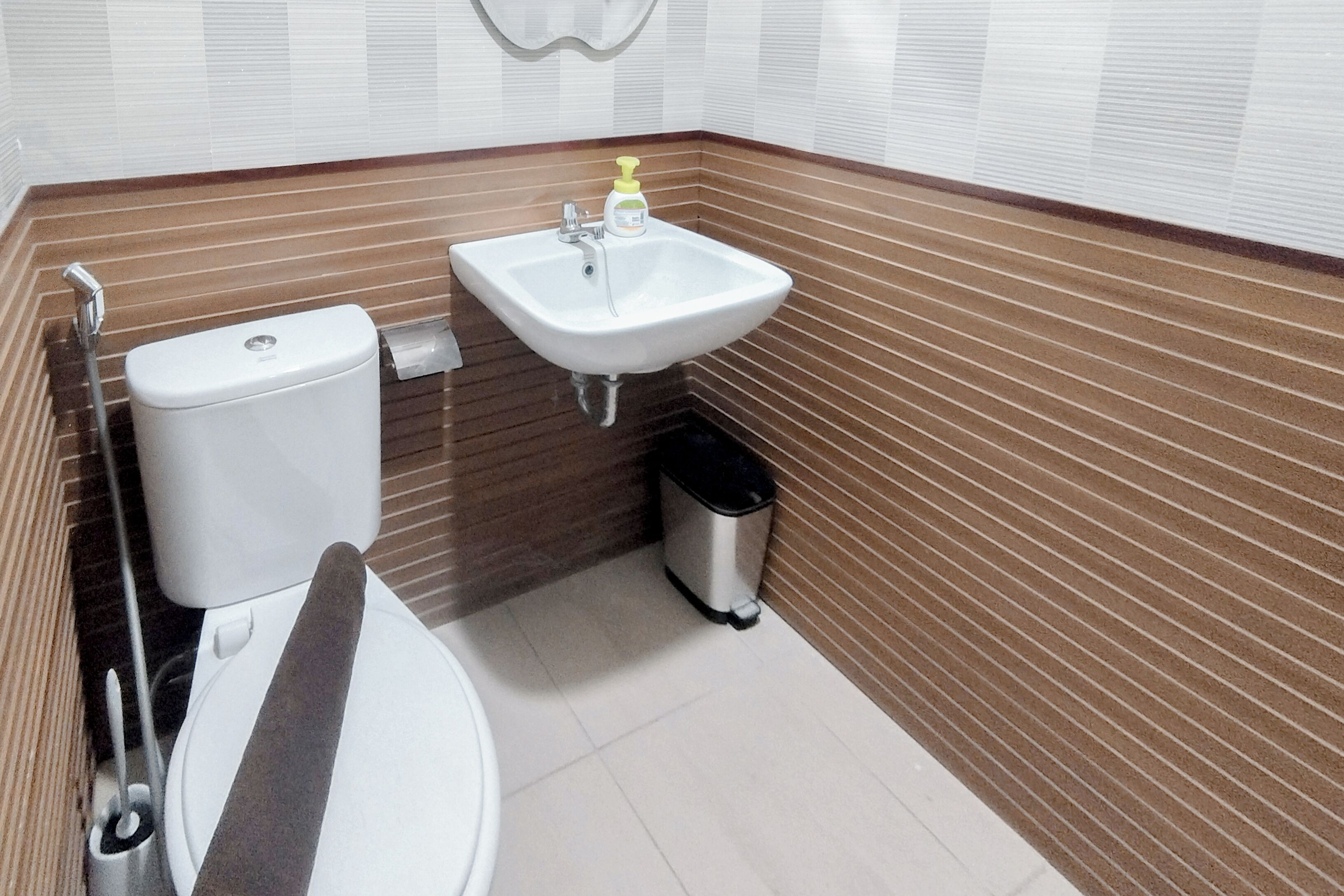 A bathroom with a toilet, sink, and trash bin.