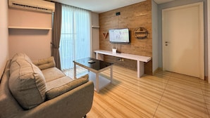 Un salon moderne avec un canapé, une table basse, un téléviseur fixé au mur en bois et une porte.