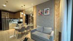 Ein modernes Wohnzimmer mit einem grauen Sofa, einem Couchtisch mit einer Pflanze sowie einem Essbereich mit Stühlen und einem Tisch.