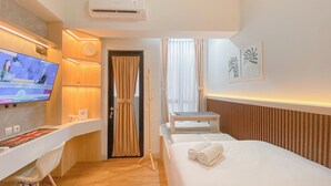 Een hotelkamer met een bed, een bureau, een televisie en een raam met gordijnen.
