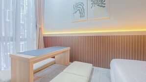 Een moderne hotelkamer met een houten bureau, een witte bank en een bed.