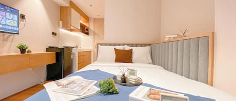 A hotel room with a bed, a desk, a television, and an air conditioning unit.
