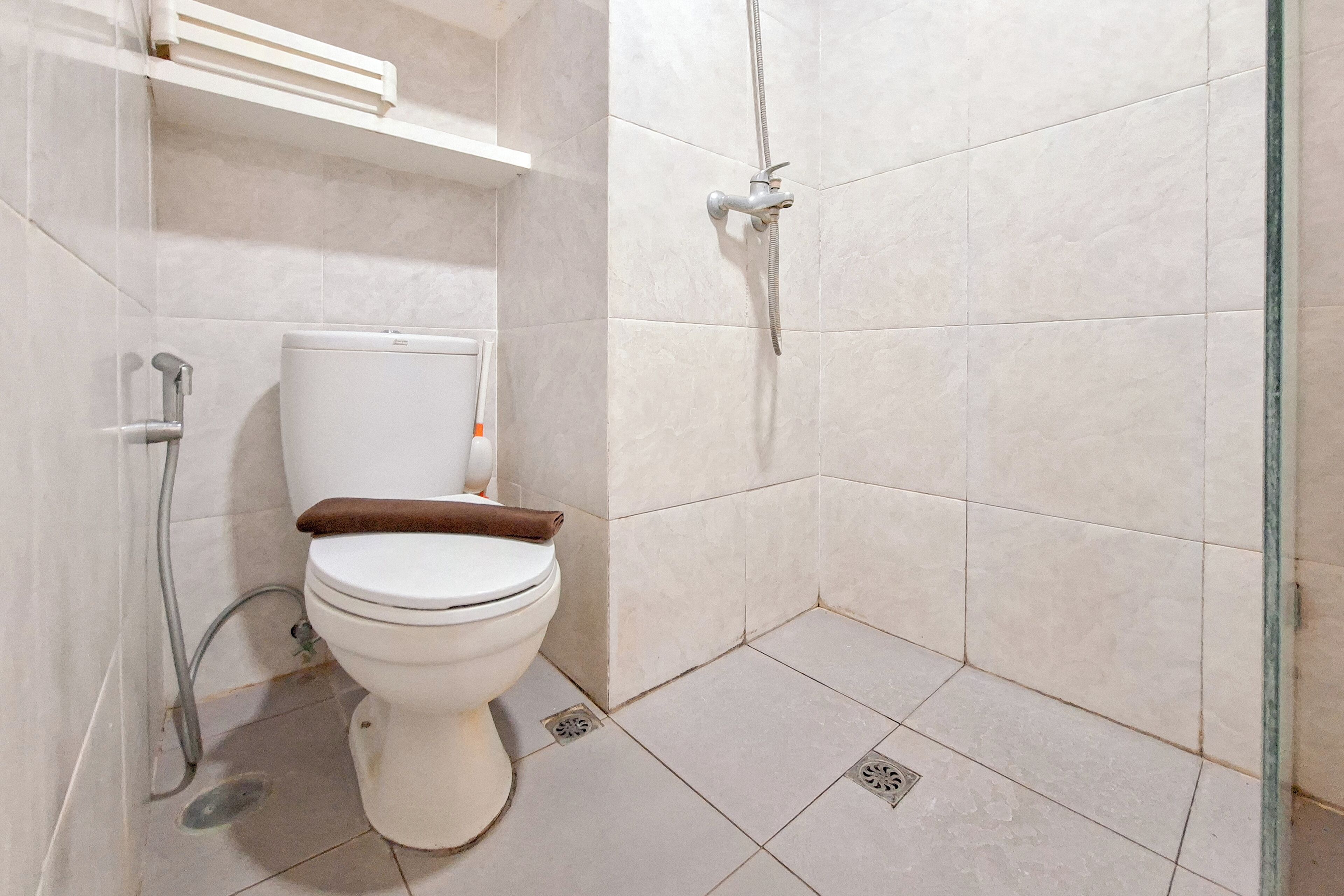 A bathroom with a toilet, a shower, and a white tiled floor.