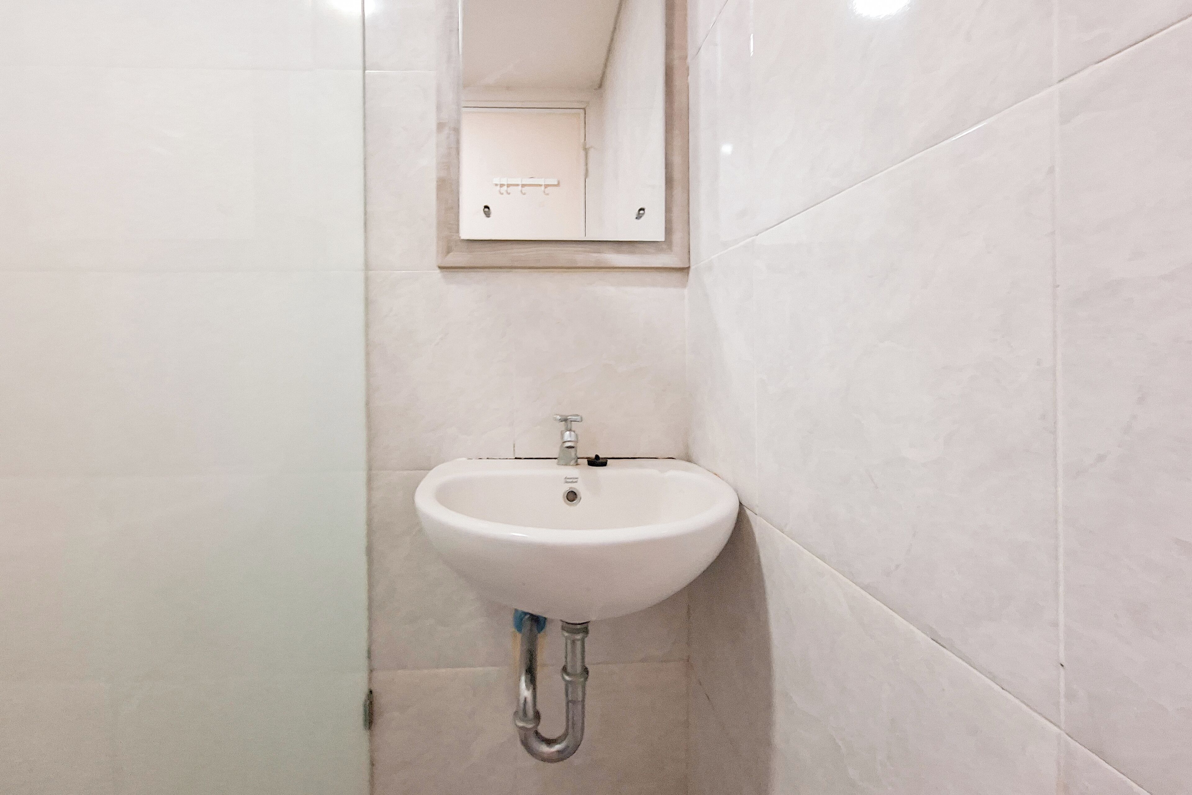 A bathroom with a white sink, a mirror, and tiled walls.