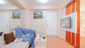 Ein modernes Schlafzimmer mit einem Bett, einem kleinen Tisch mit einer Zeitschrift, einem Fernseher an der Wand und zwei Bildern.