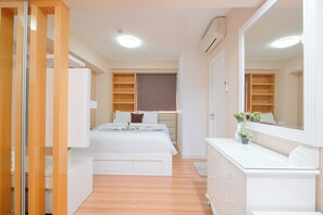 A bedroom with a bed, a dresser, a mirror, and built-in shelving.