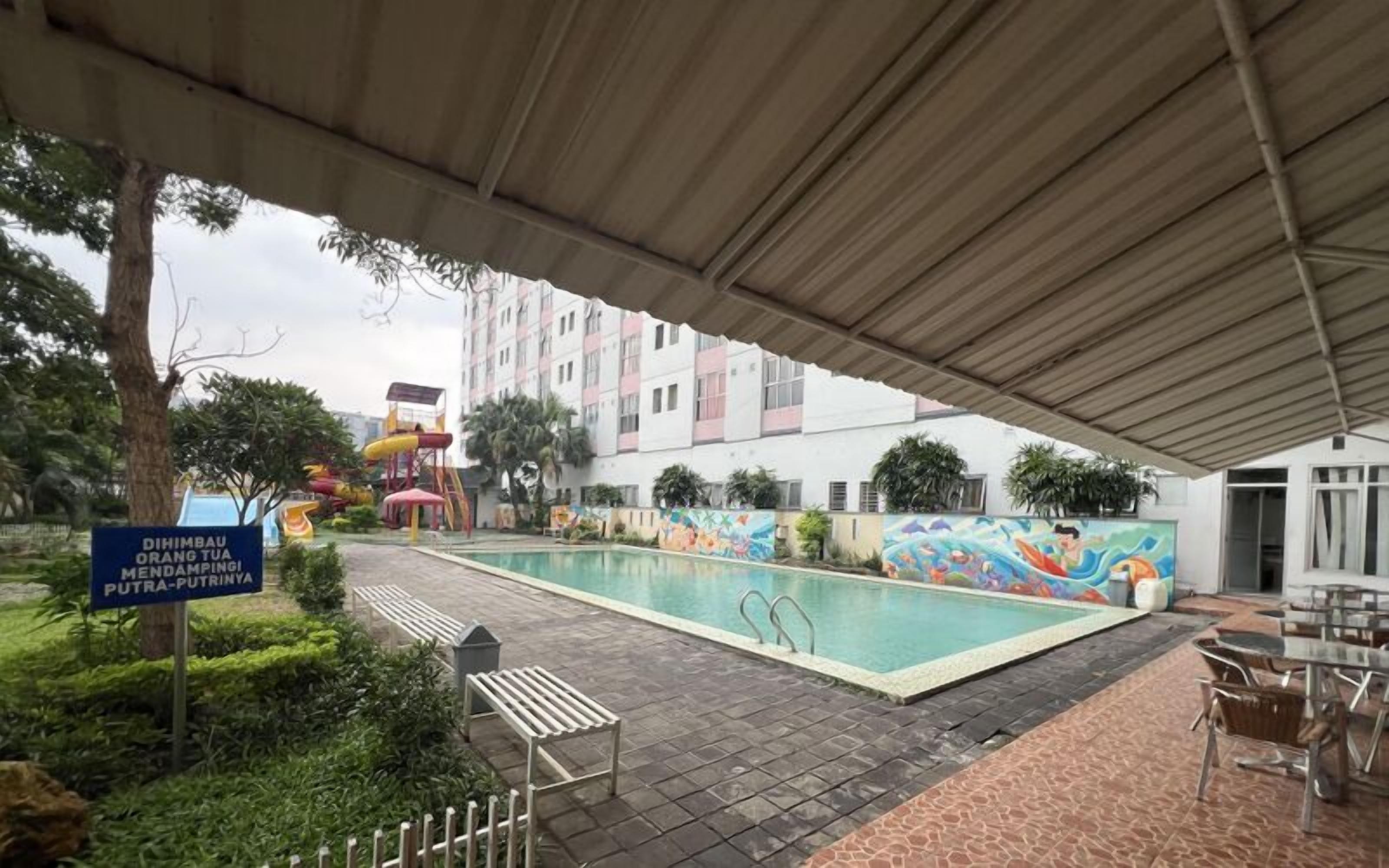 Un área de piscina techada con un mural, un tobogán acuático y un letrero que indica una zona de juegos para niños.