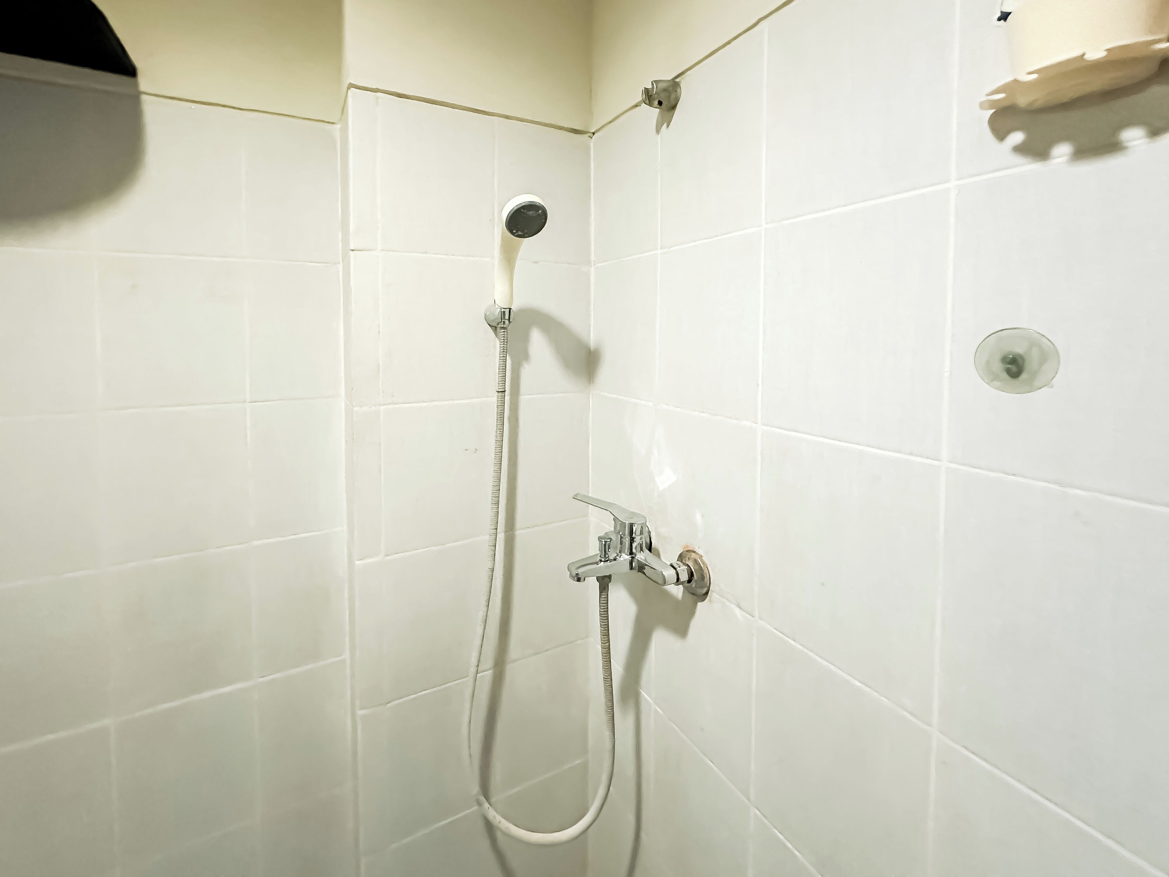 A shower with a handheld hose and a wall-mounted faucet.