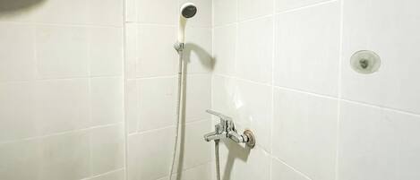 A shower with a handheld hose and a wall-mounted faucet.