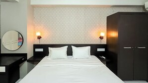 A hotel room with a large bed, two bedside tables, a wardrobe, and a mirror. - 3Br Combined Spacious At Dian Regency Apartment (Surabaya)