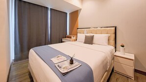 A modern hotel room with a large bed, a bedside table, a nightstand, and a window with curtains.